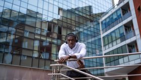 Young african american businessman leaning on railing outside office building
