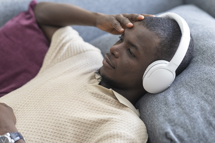 Relaxed male listening to music, reclining on cozy sofa with closed eyes