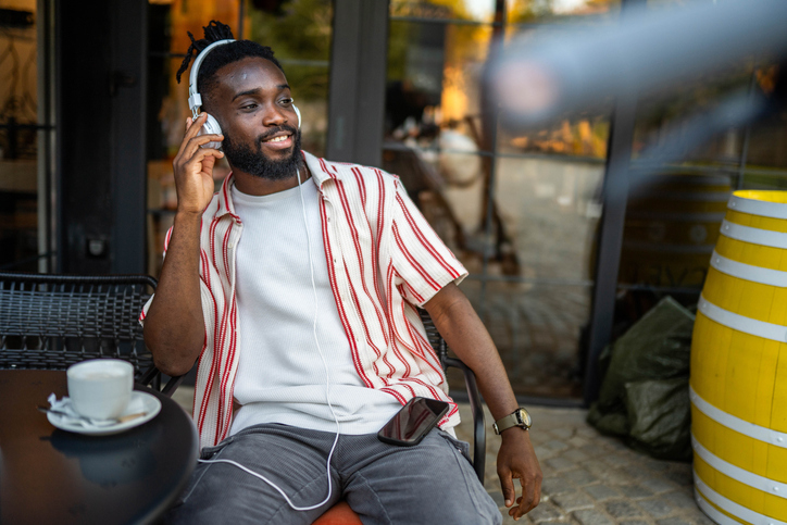 Young man enjoying music and social media at outdoor cafe