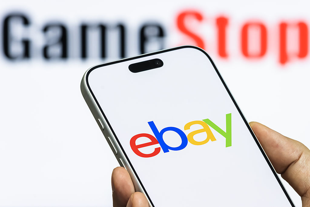 eBay Logo Shown On Smartphone With GameStop Branding In Background
