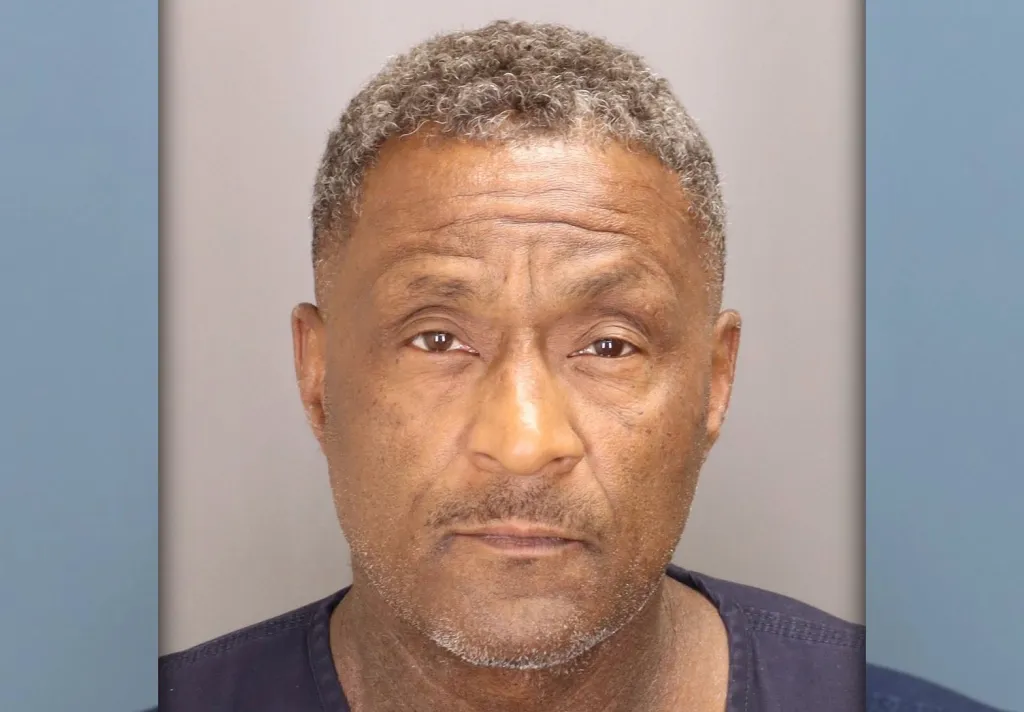 Headshot of an older African American man with gray curly hair and a serious expression.