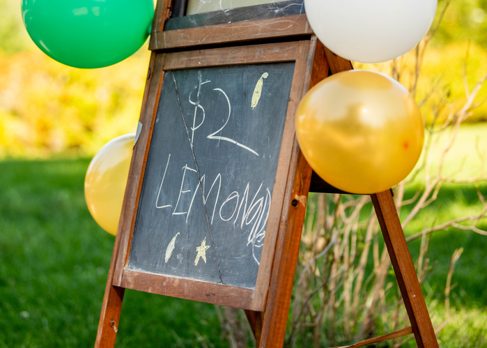 A kids' lemonade stand sign on a chalkboard