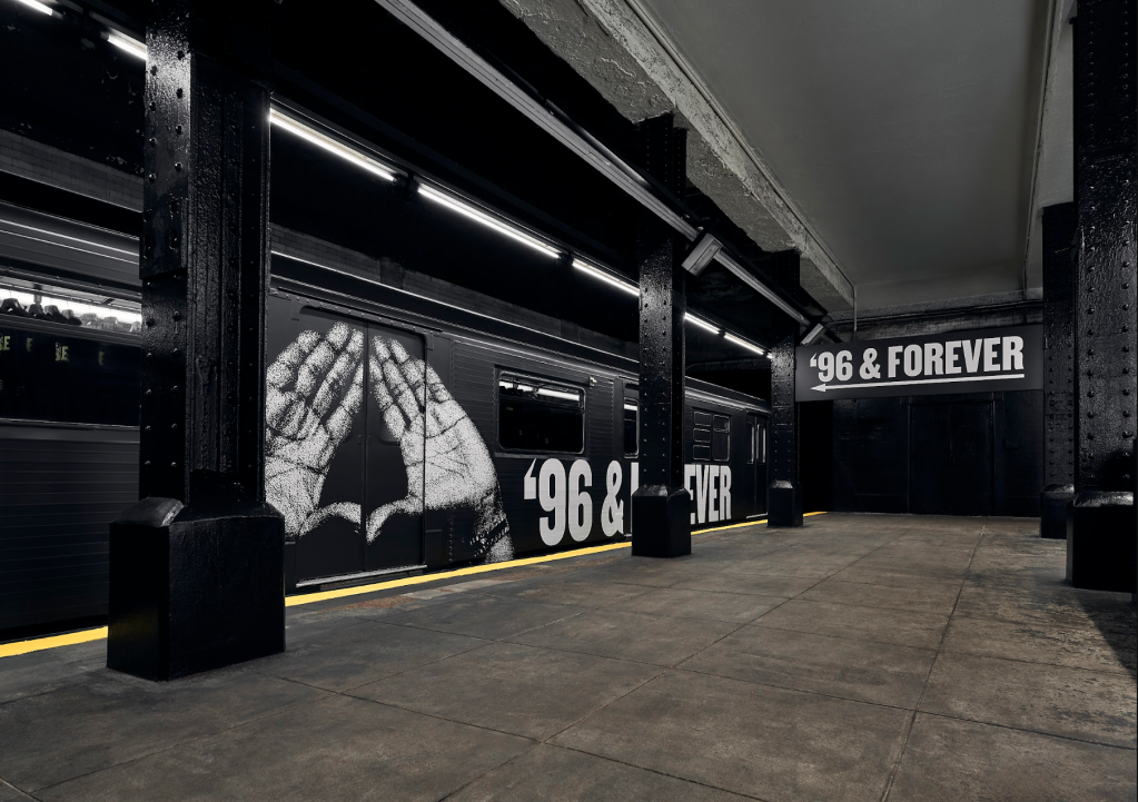 A dark, industrial-style interior space with concrete floors and columns. The walls feature large text that reads "96 & FOREVER" and a large graphic of a spider web.