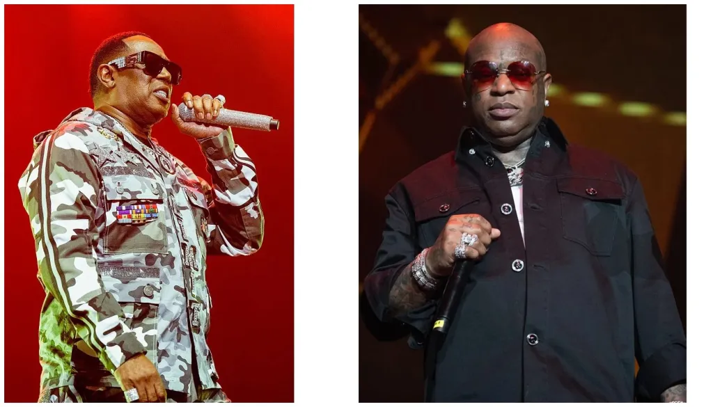 Two musicians performing on stage, one wearing a camouflage jacket and sunglasses and the other wearing a black coat and sunglasses.