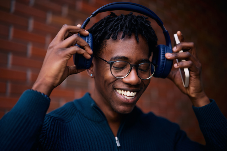 Happy black man enjoying in music over headphones.