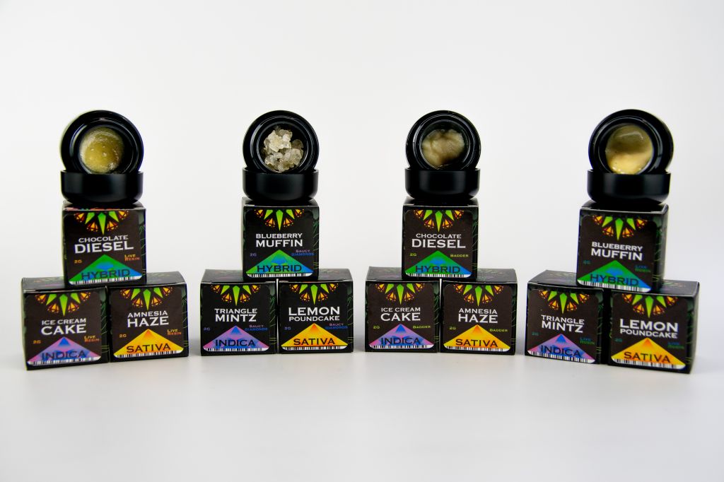 Assorted cannabis-infused edible products including chocolate, muffins, ice cream, and more, with various strain and flavor names displayed on the packaging.