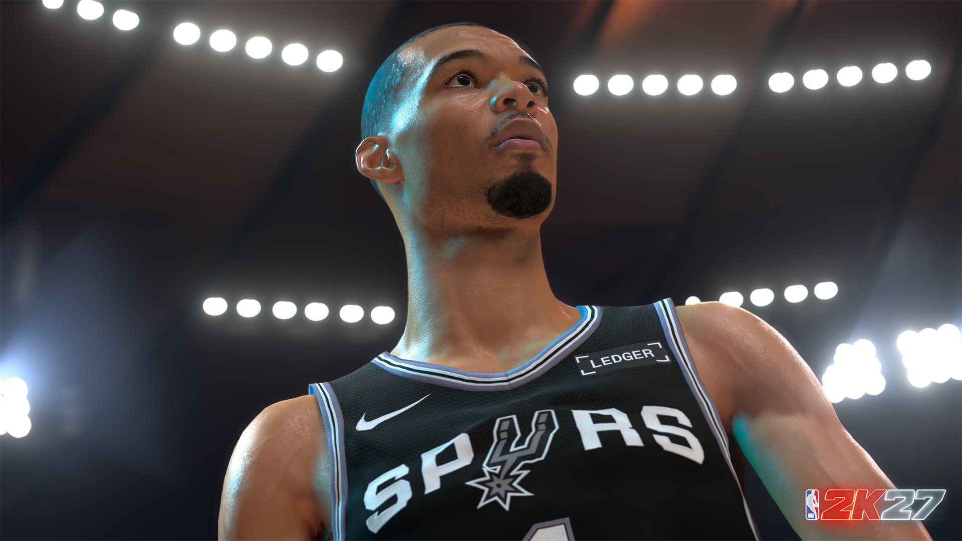 A basketball player wearing a San Antonio Spurs jersey standing on a basketball court under bright lights.