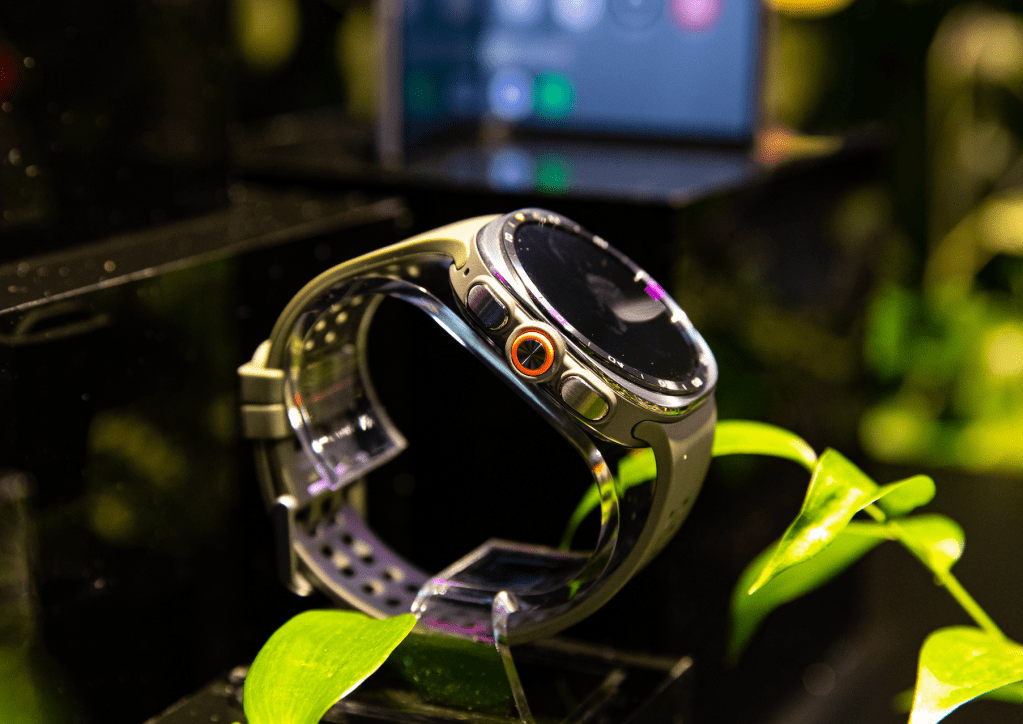A close-up view of a smartwatch with a black and silver design, featuring various buttons and sensors on the side.