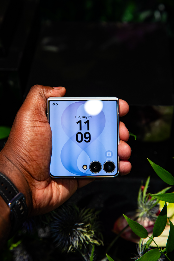 A person's hand holding a smartphone displaying the date "Tue, July 21" and the time "11:09" against a blurred natural background.