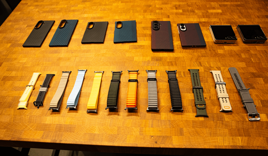 An assortment of black smartphone cases and various watch bands on a wooden table.