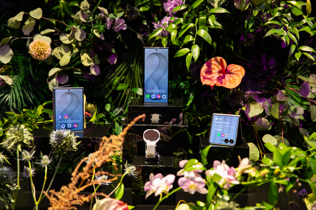 Colorful tropical flowers and plants surround three smartphones displaying various app icons and screens.