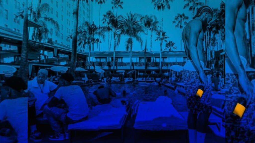 A nighttime scene at an outdoor pool area with palm trees, lounge chairs, and a large statue in the background.