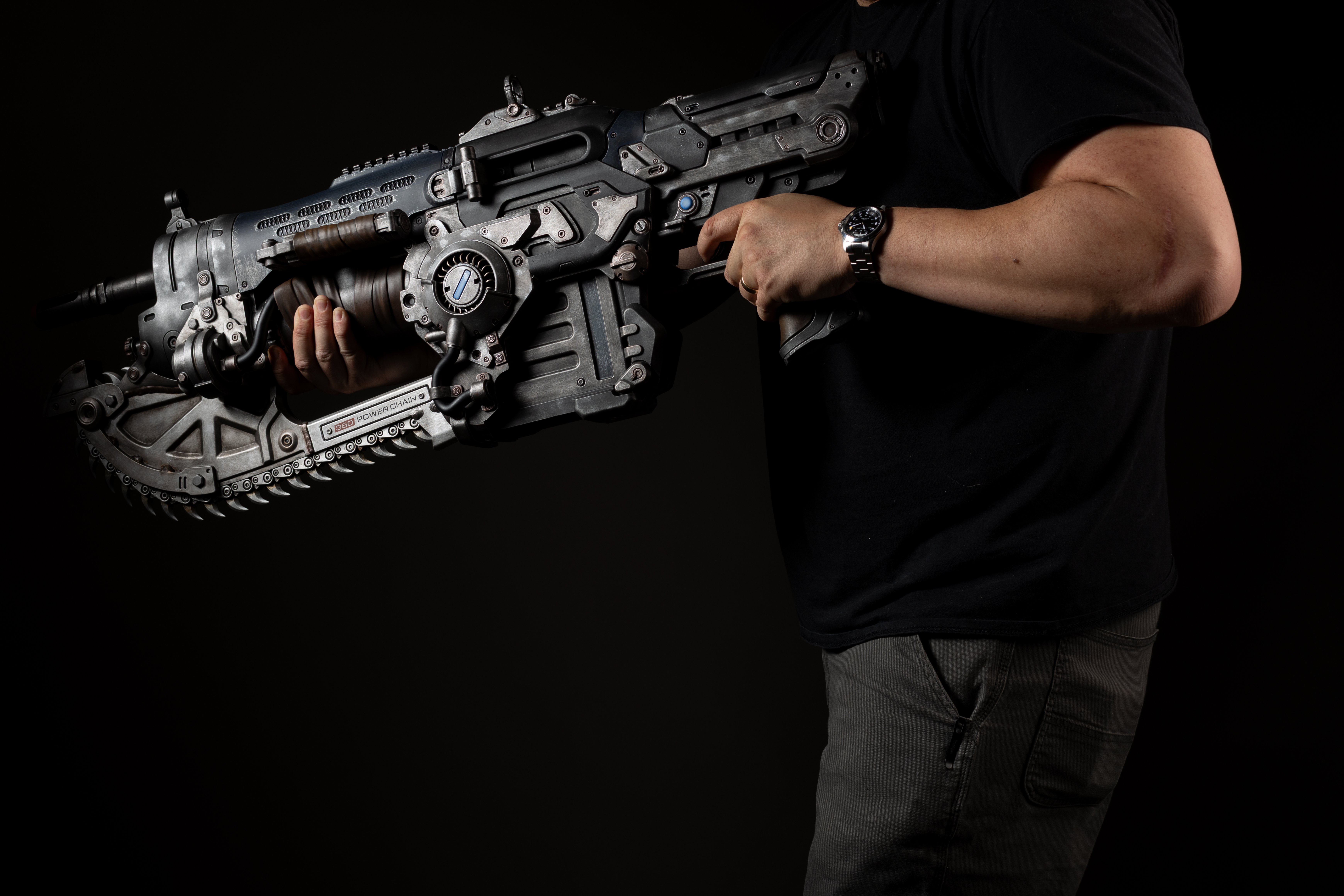 A person holding a futuristic-looking assault rifle in a dark setting.