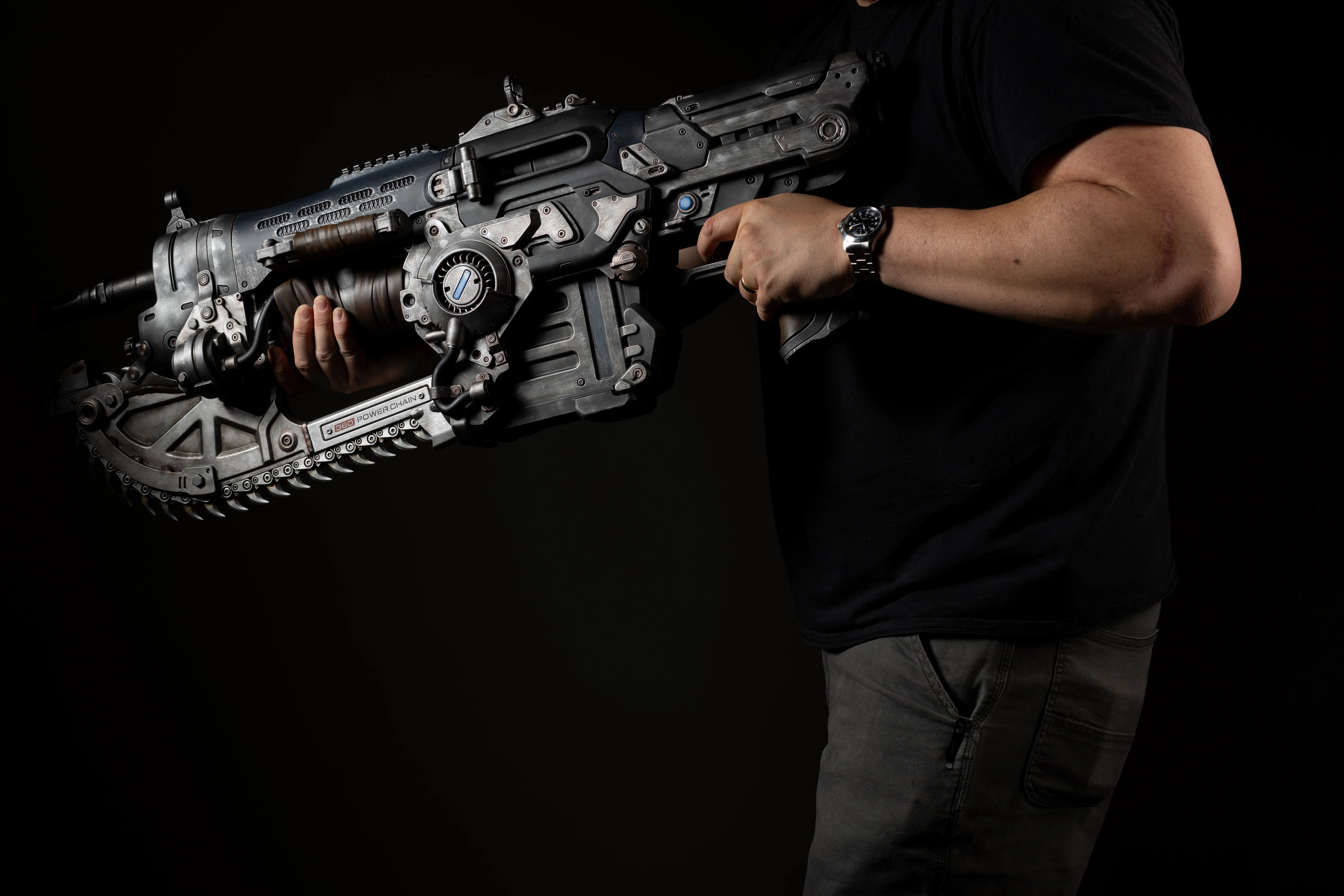 A person holding a futuristic-looking assault rifle in a dark setting.